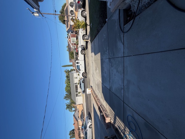 View across a concrete driveway and walkway toward an Antioch street